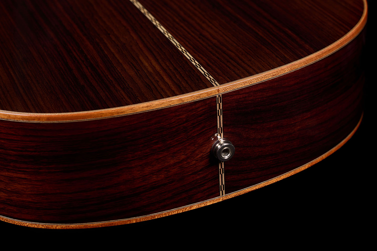 Close-up of the Orchestra CE Pro's endpin jack set into the rosewood back's center seam.
