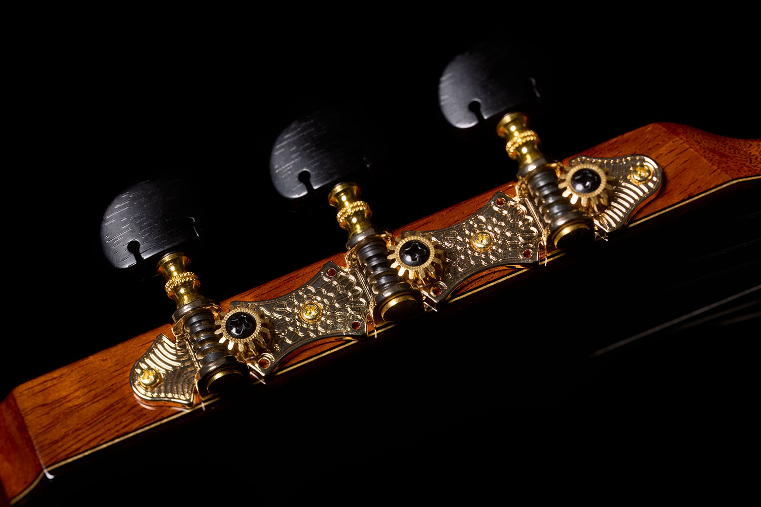 Close-up of the headstock, showing the ornate gold tuning machines with dark oval buttons of the Orchestra CE Pro.