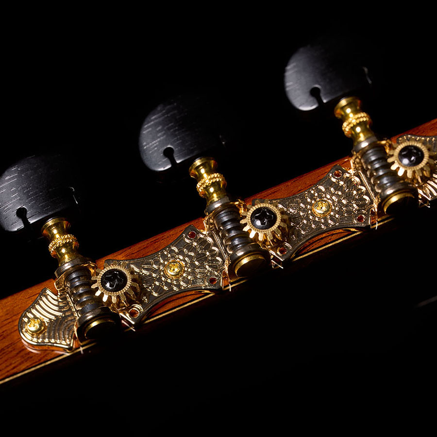 Close-up of the headstock, showing the ornate gold tuning machines with dark oval buttons of the Orchestra CE Pro.