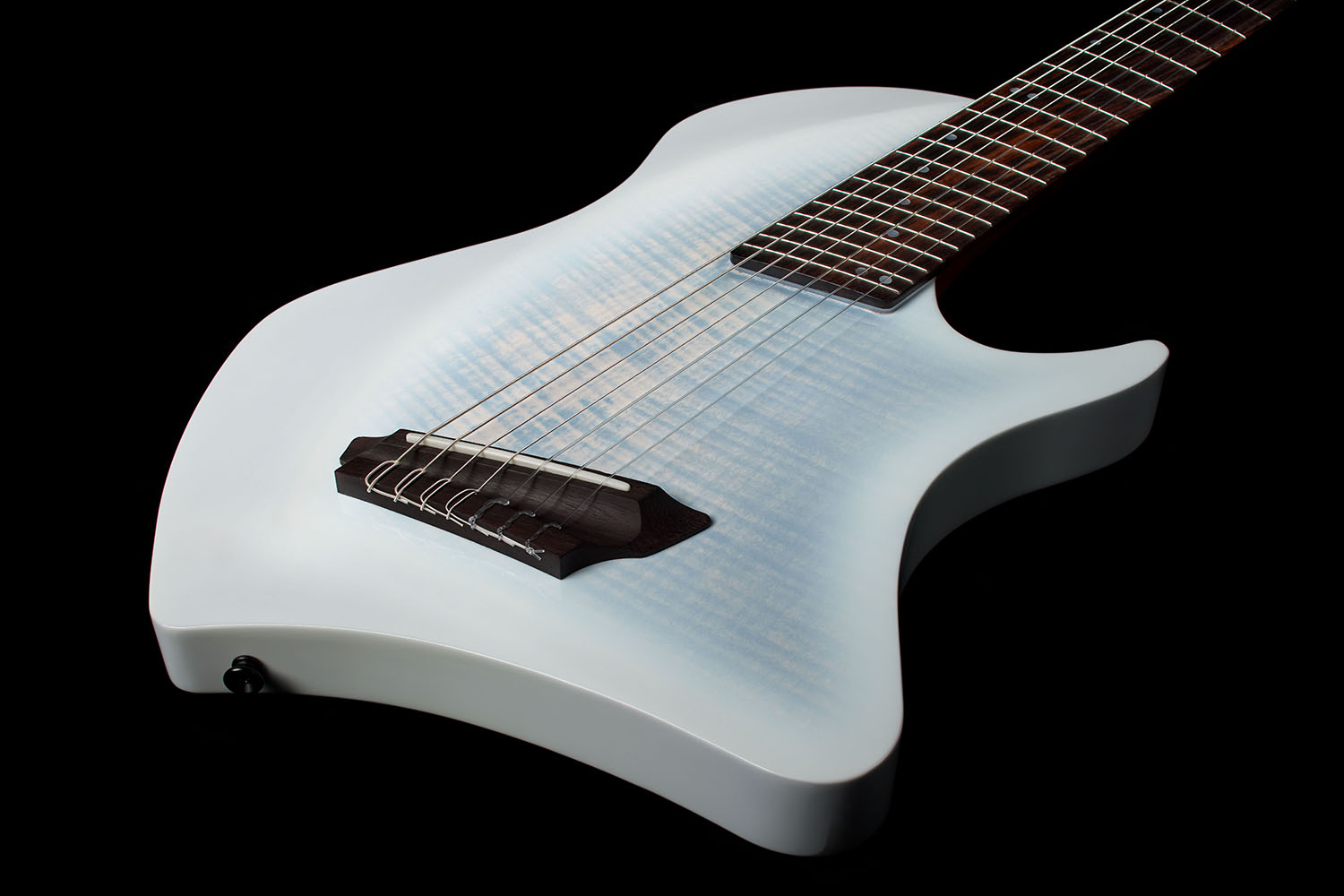 Angled top-down view of the Abasi Stage 7 White Burst's flame maple top, showing the oval side sound hole, bridge, and side-mounted control knob.