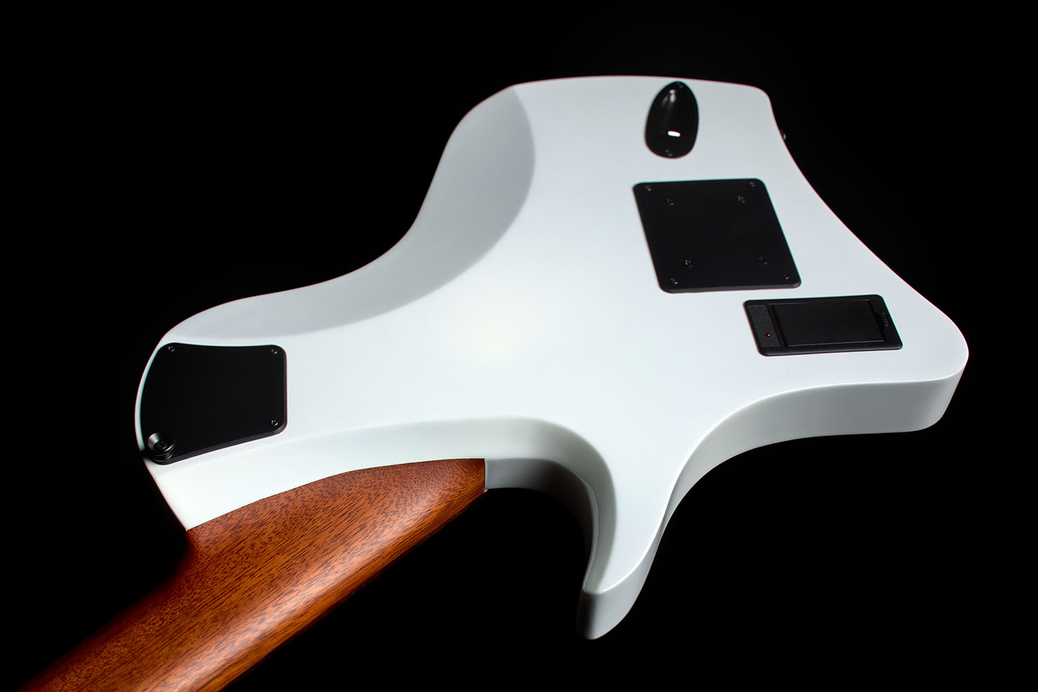 Close-up of the Abasi Stage 7 White Burst's back and neck heel, showing the mahogany neck joint and a black control cover against the white gloss finish.