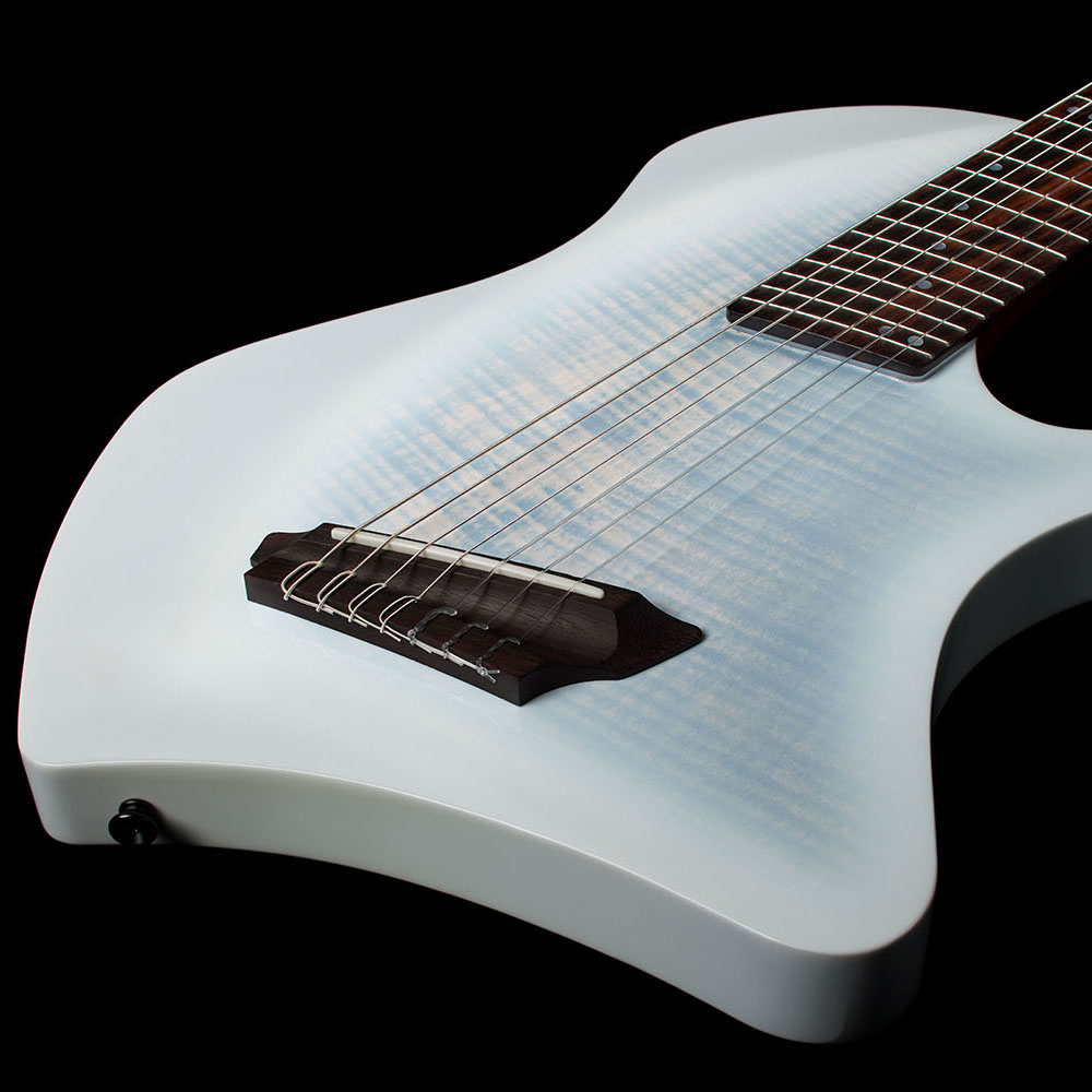 Angled top-down view of the Abasi Stage 7 White Burst's flame maple top, showing the oval side sound hole, bridge, and side-mounted control knob.
