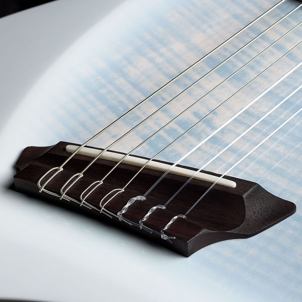 Close-up of the Abasi Stage 7 White Burst's rosewood bridge and bone saddle, showing the flame maple top's figured grain and blue-white burst coloring.