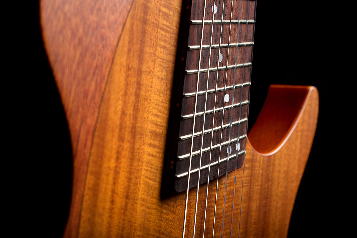 Close-up of the Abasi Stage 7 Acacia's neck heel and body edge, showing the fanned frets and cutaway body.