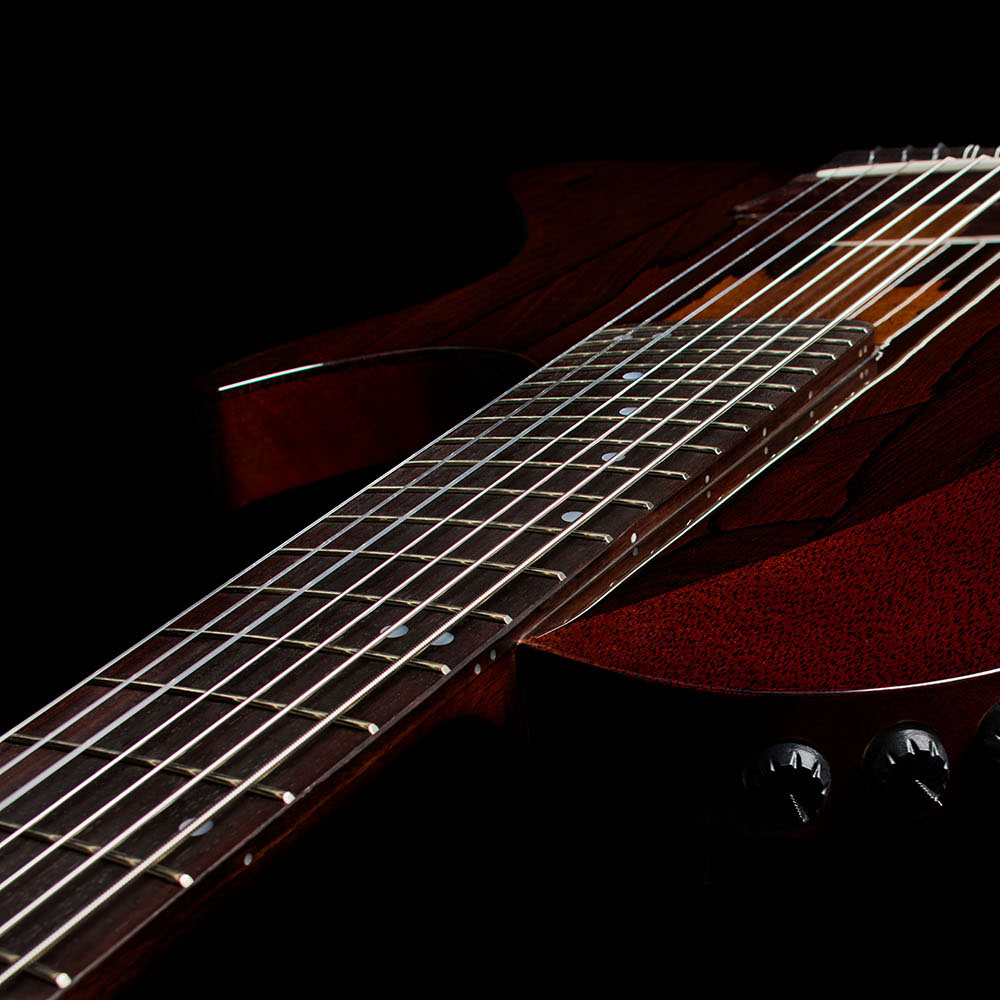 Close-up of the Abasi Stage 7 Ziricote's neck and bridge area with the side-mounted volume and EQ control knobs visible.