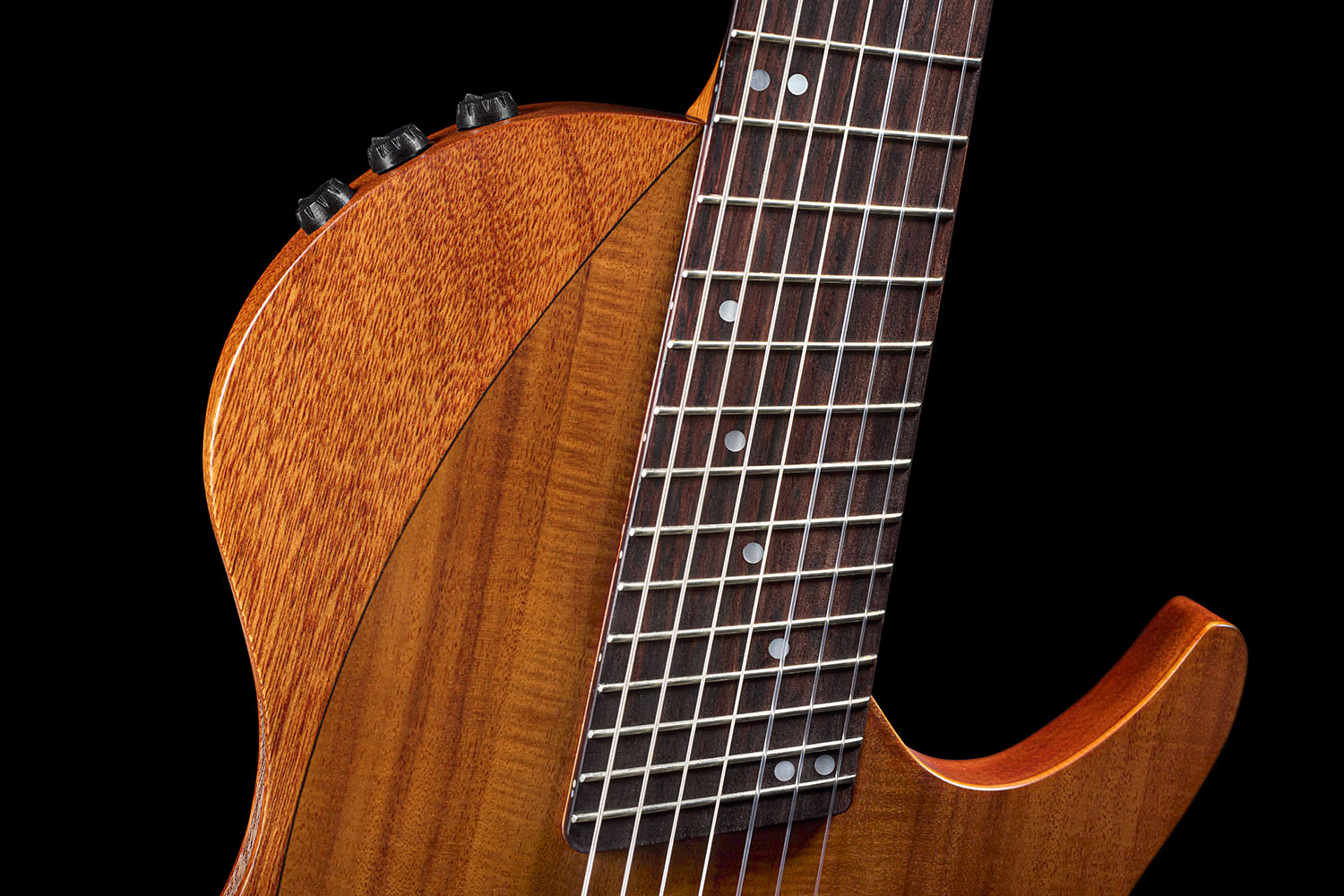 Close-up of the Abasi Stage 7 Acacia's rosewood fretboard and mahogany neck meeting the guitar's ergonomic cutaway body.
