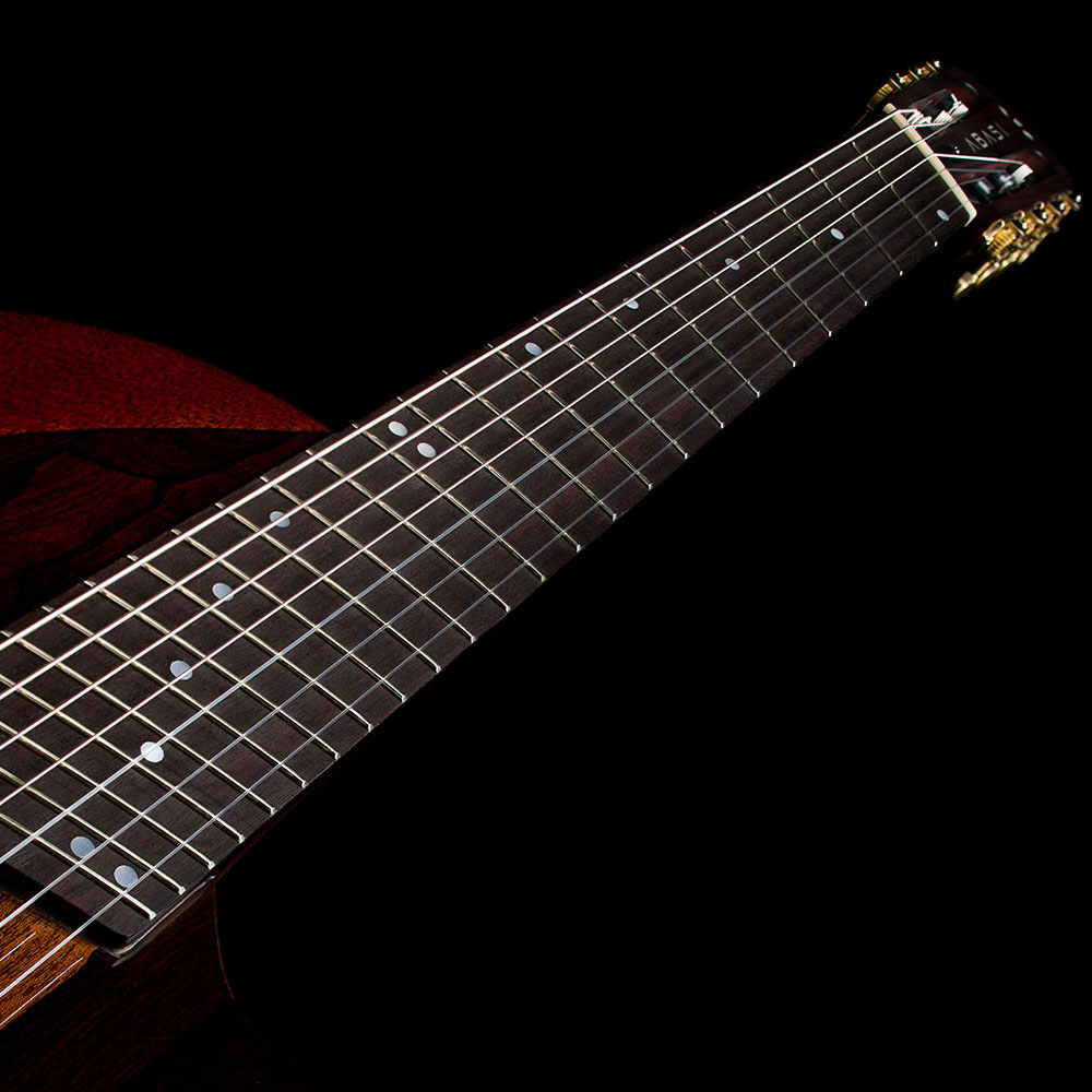 Close-up looking up the rosewood fretboard toward the Abasi Stage 7 Ziricote's headstock, showing the fanned frets and dot inlays.
