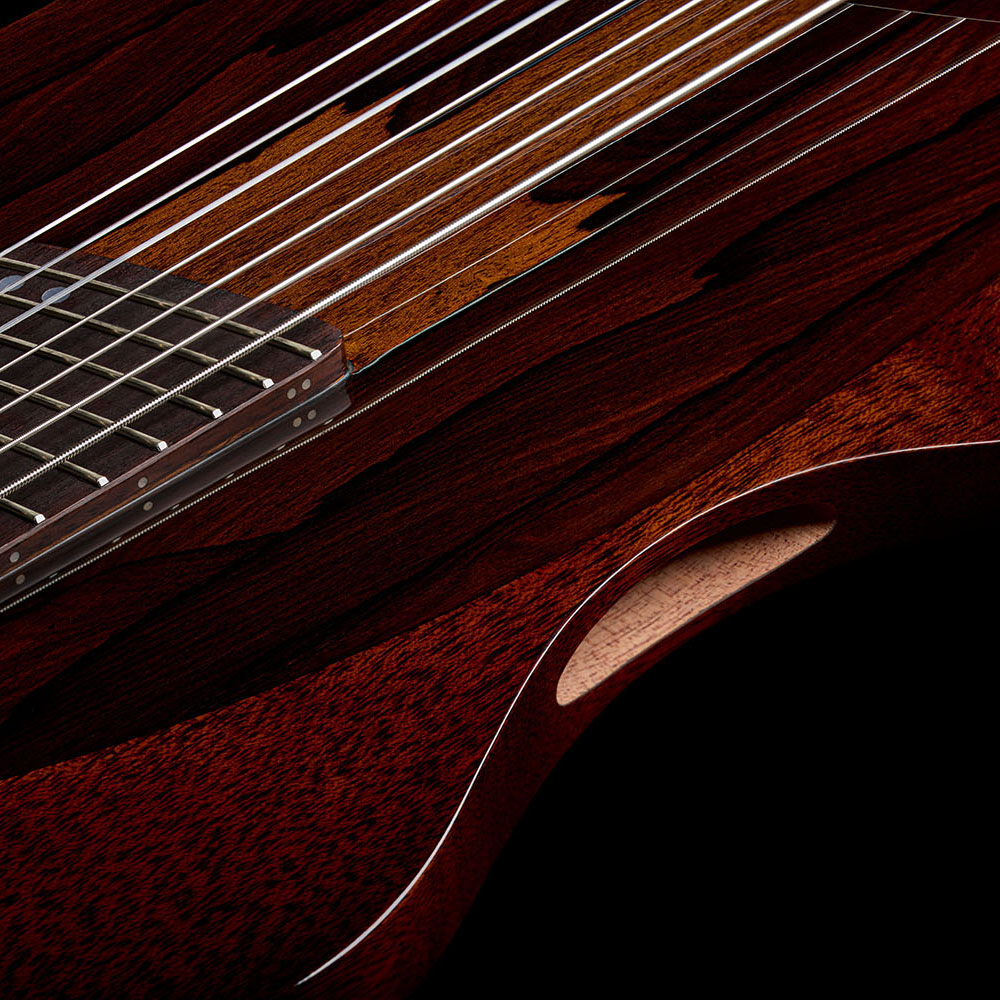 Close-up of the Abasi Stage 7 Ziricote's lower bout, showing the ziricote veneer's reddish streaked grain around the bridge.