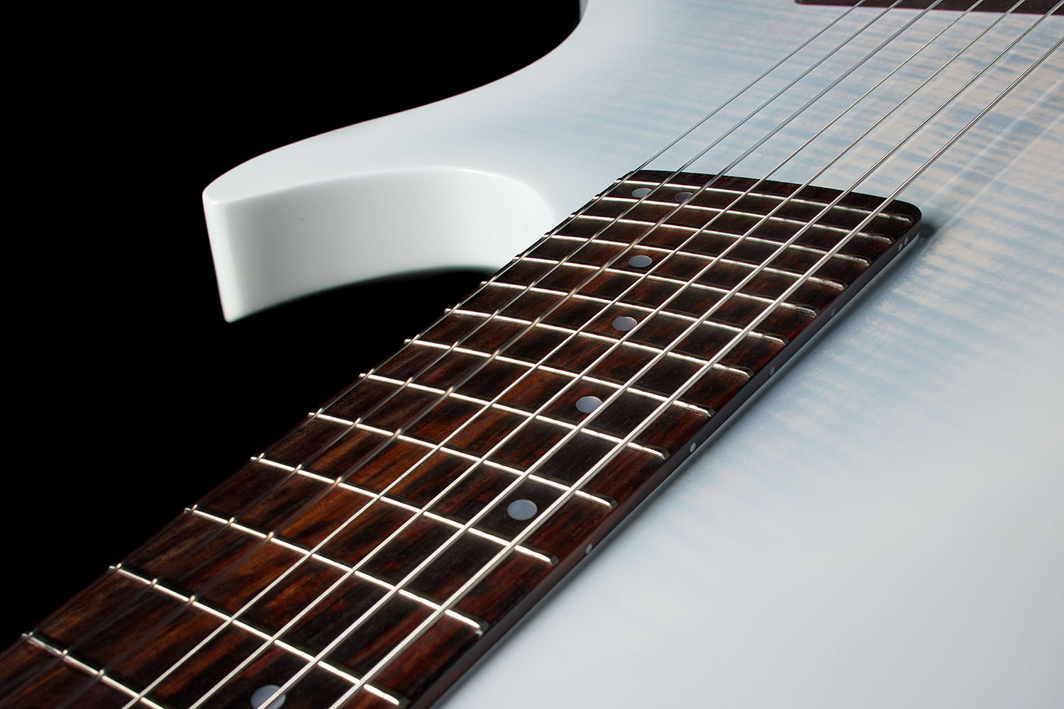 Close-up of the Abasi Stage 7 White Burst's upper cutaway horn and fretboard, showing the fanned frets against the white gloss body.