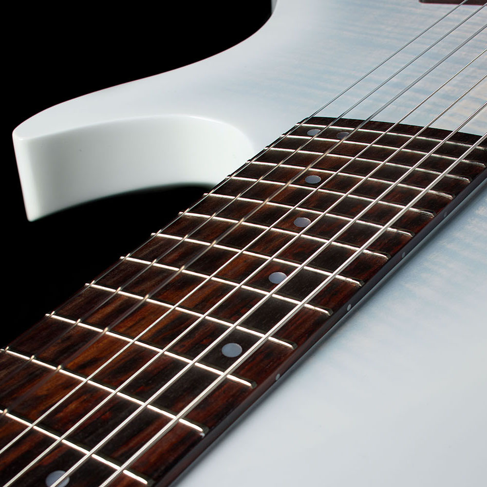Close-up of the Abasi Stage 7 White Burst's upper cutaway horn and fretboard, showing the fanned frets against the white gloss body.