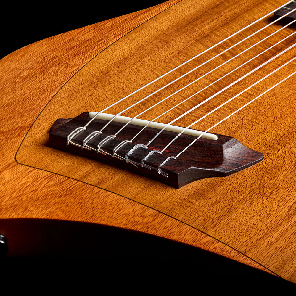 Close-up of the Abasi Stage 7 Acacia's bridge and lower bout, showing the acacia top veneer grain and side-mounted control knob.