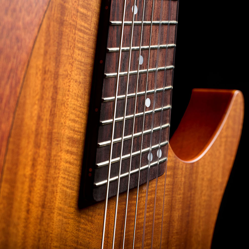 Close-up of the Abasi Stage 7 Acacia's neck heel and body edge, showing the fanned frets and cutaway body.