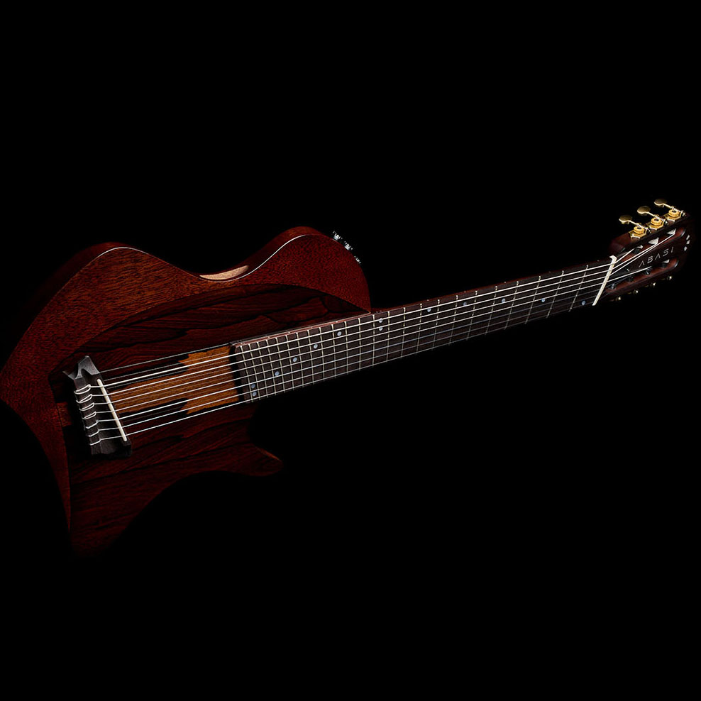 Full side-profile view of the Abasi Stage 7 Ziricote, showing the thin chambered body, fanned headstock, and brass tuners.