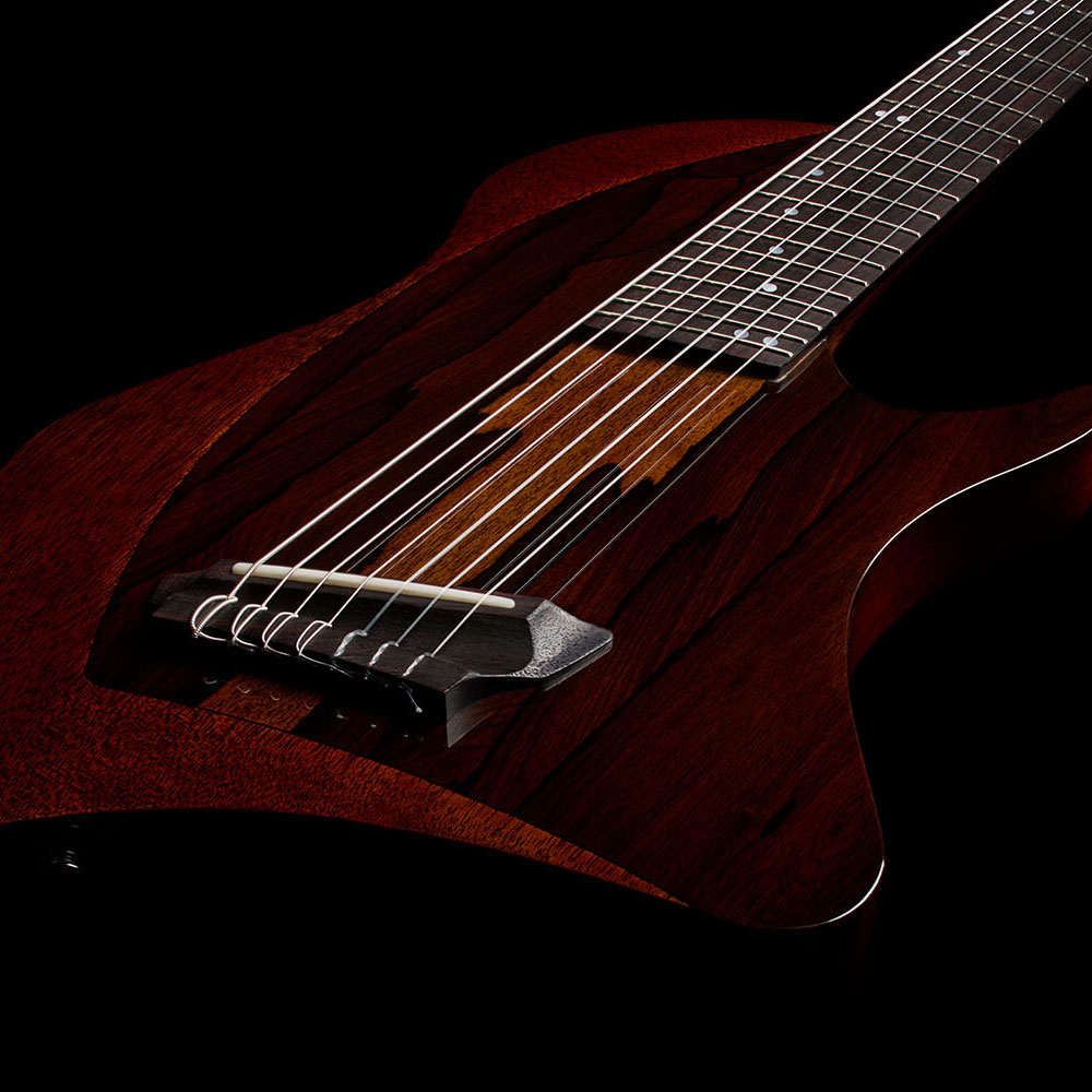Close-up of the Abasi Stage 7 Ziricote's bridge and strings, showing the ziricote top veneer grain and neck joint.