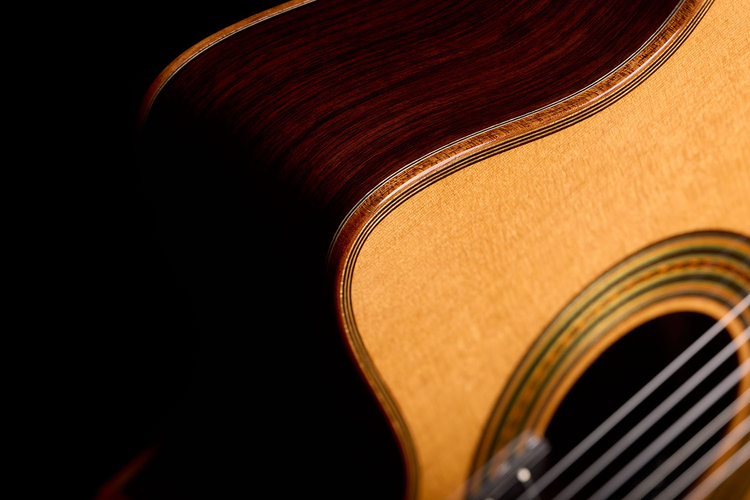 Close-up of the Orchestra CE Pro showing the rosewood side curving into the spruce top edge.