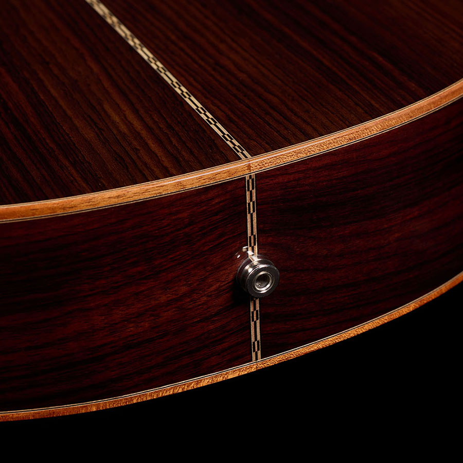 Close-up of the Orchestra CE Pro's endpin jack set into the rosewood back's center seam.